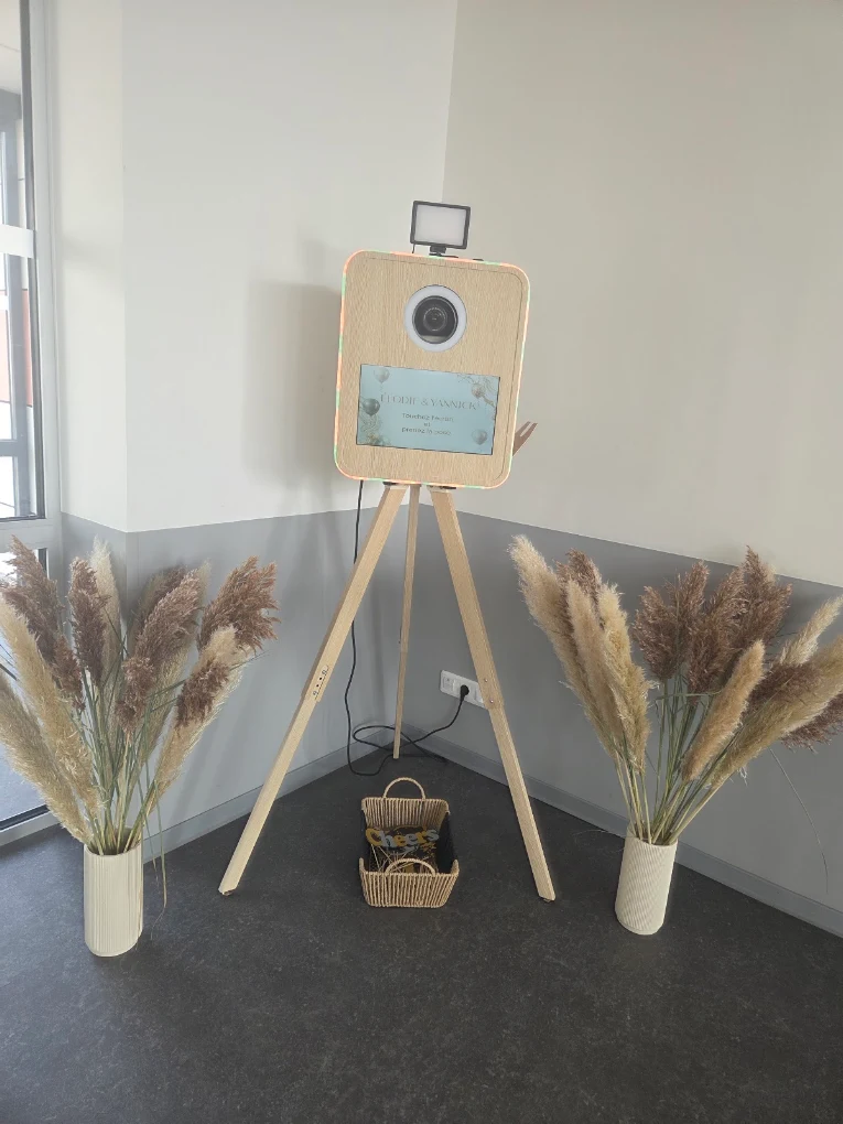 Photobooth en bois installé pour un mariage, écran d'accueil personnalisé aux prénoms des mariés